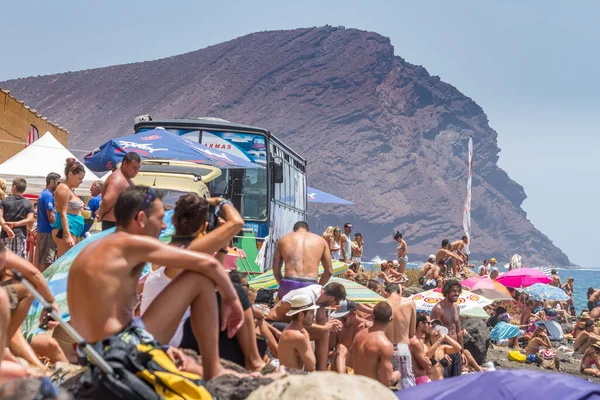 TENERİFE, SPAIN 11 - AGUSTAN 2013: Bir grup insan günü plajda şemsiyelerle, mayolarıyla, güneşlenerek, sahilde yüzerek ve kıyıdan badiba şampiyonasını izleyerek geçiriyorlar. Tenerife, Kanarya Adaları, Sp