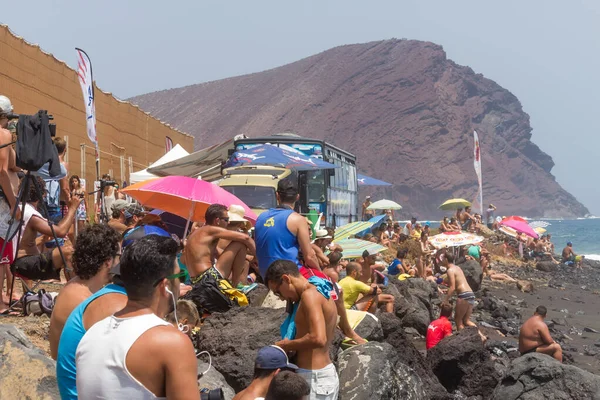 TENERİFE, SPAIN 11 - AGUSTAN 2013: Bir grup insan günü plajda şemsiyelerle, mayolarıyla, güneşlenerek, sahilde yüzerek ve kıyıdan badiba şampiyonasını izleyerek geçiriyorlar. Tenerife, Kanarya Adaları, Sp