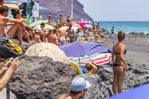 TENERİFE, SPAIN 11 - AGUSTAN 2013: Bir grup insan günü plajda şemsiyelerle, mayolarıyla, güneşlenerek, sahilde yüzerek ve kıyıdan badiba şampiyonasını izleyerek geçiriyorlar. Tenerife, Kanarya Adaları, Sp