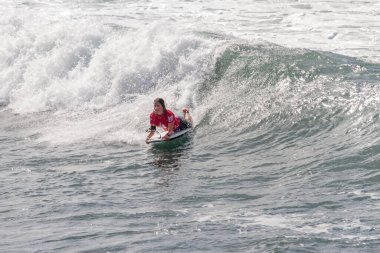 TENERIFE, SPAIN, NOVEMBER-03-2013: Sörfçü kız bir yarışmada, beyaz köpüklü sörf tahtası ile çeşitli manevralar yapar. Tenerife, Kanarya Adaları, İspanya