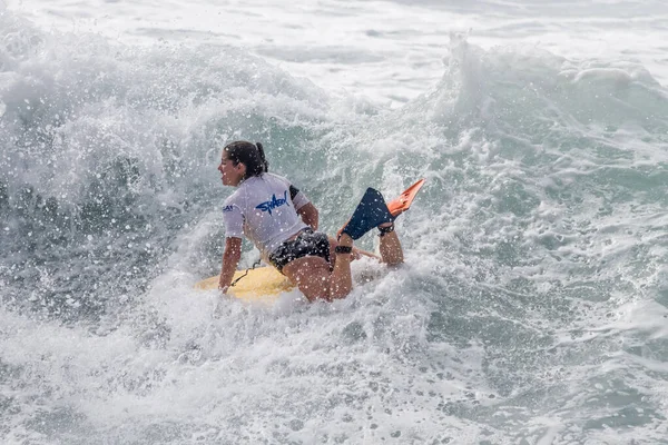 TENERIFE, SPAIN, NOVEMBER-03-2013: Sörfçü kız bir yarışmada, beyaz köpüklü sörf tahtası ile çeşitli manevralar yapar. Tenerife, Kanarya Adaları, İspanya
