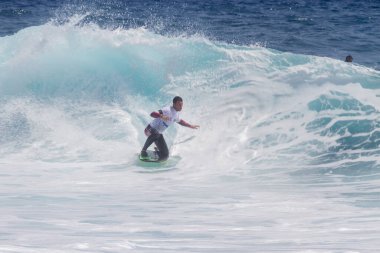 TENERIFE, SPAIN 11 - HAZİRAN 2013: Erkekler vücut tahtası şampiyonasında yarışan bir çocuğun dalgada dizlerinin üzerinde sörf yaparken farklı ve inanılmaz manevralar ve dönüşler yaparak bir sürü köpük oluşturduğu açık çekim. Tenerife, Kanarya Adaları, İspanya