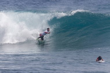 TENERIFE, SPAIN 11 - HAZİRAN 2013: Erkekler vücut tahtası şampiyonasında yarışan bir çocuğun dalgada dizlerinin üzerinde sörf yaparken farklı ve inanılmaz manevralar ve dönüşler yaparak bir sürü köpük oluşturduğu açık çekim. Tenerife, Kanarya Adaları, İspanya