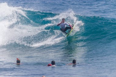 TENERIFE, SPAIN 11 - HAZİRAN 2013: Erkekler vücut tahtası şampiyonasında yarışan bir çocuğun dalgada dizlerinin üzerinde sörf yaparken farklı ve inanılmaz manevralar ve dönüşler yaparak bir sürü köpük oluşturduğu açık çekim. Tenerife, Kanarya Adaları, İspanya
