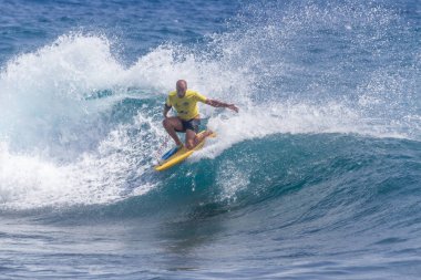 TENERIFE, SPAIN 11 - HAZİRAN 2013: Erkekler vücut tahtası şampiyonasında yarışan bir çocuğun dalgada dizlerinin üzerinde sörf yaparken farklı ve inanılmaz manevralar ve dönüşler yaparak bir sürü köpük oluşturduğu açık çekim. Tenerife, Kanarya Adaları, İspanya