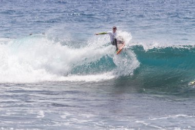 TENERIFE, SPAIN 11 - HAZİRAN 2013: Erkekler vücut tahtası şampiyonasında yarışan bir çocuğun dalgada dizlerinin üzerinde sörf yaparken farklı ve inanılmaz manevralar ve dönüşler yaparak bir sürü köpük oluşturduğu açık çekim. Tenerife, Kanarya Adaları, İspanya