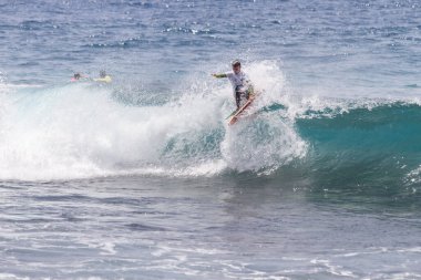 TENERIFE, SPAIN 11 - HAZİRAN 2013: Erkekler vücut tahtası şampiyonasında yarışan bir çocuğun dalgada dizlerinin üzerinde sörf yaparken farklı ve inanılmaz manevralar ve dönüşler yaparak bir sürü köpük oluşturduğu açık çekim. Tenerife, Kanarya Adaları, İspanya