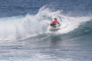 TENERIFE, SPAIN 11 - HAZİRAN 2013: Erkekler vücut tahtası şampiyonasında yarışan bir çocuğun dalgada dizlerinin üzerinde sörf yaparken farklı ve inanılmaz manevralar ve dönüşler yaparak bir sürü köpük oluşturduğu açık çekim. Tenerife, Kanarya Adaları, İspanya