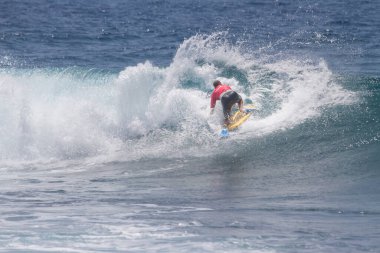 TENERIFE, SPAIN 11 - HAZİRAN 2013: Erkekler vücut tahtası şampiyonasında yarışan bir çocuğun dalgada dizlerinin üzerinde sörf yaparken farklı ve inanılmaz manevralar ve dönüşler yaparak bir sürü köpük oluşturduğu açık çekim. Tenerife, Kanarya Adaları, İspanya