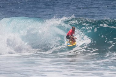 TENERIFE, SPAIN 11 - HAZİRAN 2013: Erkekler vücut tahtası şampiyonasında yarışan bir çocuğun dalgada dizlerinin üzerinde sörf yaparken farklı ve inanılmaz manevralar ve dönüşler yaparak bir sürü köpük oluşturduğu açık çekim. Tenerife, Kanarya Adaları, İspanya