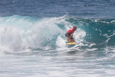 TENERIFE, SPAIN 11 - HAZİRAN 2013: Erkekler vücut tahtası şampiyonasında yarışan bir çocuğun dalgada dizlerinin üzerinde sörf yaparken farklı ve inanılmaz manevralar ve dönüşler yaparak bir sürü köpük oluşturduğu açık çekim. Tenerife, Kanarya Adaları, İspanya