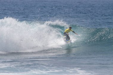 TENERIFE, SPAIN 11 - HAZİRAN 2013: Erkekler vücut tahtası şampiyonasında yarışan bir çocuğun dalgada dizlerinin üzerinde sörf yaparken farklı ve inanılmaz manevralar ve dönüşler yaparak bir sürü köpük oluşturduğu açık çekim. Tenerife, Kanarya Adaları, İspanya