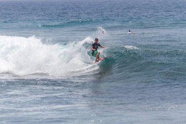 TENERIFE, SPAIN 11 - HAZİRAN 2013: Erkekler vücut tahtası şampiyonasında yarışan bir çocuğun dalgada dizlerinin üzerinde sörf yaparken farklı ve inanılmaz manevralar ve dönüşler yaparak bir sürü köpük oluşturduğu açık çekim. Tenerife, Kanarya Adaları, İspanya