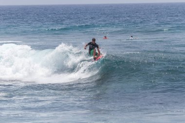 TENERIFE, SPAIN 11 - HAZİRAN 2013: Erkekler vücut tahtası şampiyonasında yarışan bir çocuğun dalgada dizlerinin üzerinde sörf yaparken farklı ve inanılmaz manevralar ve dönüşler yaparak bir sürü köpük oluşturduğu açık çekim. Tenerife, Kanarya Adaları, İspanya