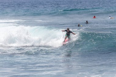 TENERIFE, SPAIN 11 - HAZİRAN 2013: Erkekler vücut tahtası şampiyonasında yarışan bir çocuğun dalgada dizlerinin üzerinde sörf yaparken farklı ve inanılmaz manevralar ve dönüşler yaparak bir sürü köpük oluşturduğu açık çekim. Tenerife, Kanarya Adaları, İspanya