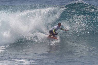 TENERIFE, SPAIN 11 - HAZİRAN 2013: Erkekler vücut tahtası şampiyonasında yarışan bir çocuğun dalgada dizlerinin üzerinde sörf yaparken farklı ve inanılmaz manevralar ve dönüşler yaparak bir sürü köpük oluşturduğu açık çekim. Tenerife, Kanarya Adaları, Spai