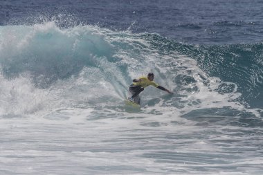 TENERIFE, SPAIN 11 - HAZİRAN 2013: Erkekler vücut tahtası şampiyonasında yarışan bir çocuğun dalgada dizlerinin üzerinde sörf yaparken farklı ve inanılmaz manevralar ve dönüşler yaparak bir sürü köpük oluşturduğu açık çekim. Tenerife, Kanarya Adaları, Spai
