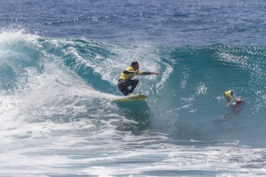 TENERIFE, SPAIN 11 - HAZİRAN 2013: Erkekler vücut tahtası şampiyonasında yarışan bir çocuğun dalgada dizlerinin üzerinde sörf yaparken farklı ve inanılmaz manevralar ve dönüşler yaparak bir sürü köpük oluşturduğu açık çekim. Tenerife, Kanarya Adaları, Spai