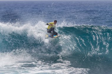 TENERIFE, SPAIN 11 - HAZİRAN 2013: Erkekler vücut tahtası şampiyonasında yarışan bir çocuğun dalgada dizlerinin üzerinde sörf yaparken farklı ve inanılmaz manevralar ve dönüşler yaparak bir sürü köpük oluşturduğu açık çekim. Tenerife, Kanarya Adaları, Spai