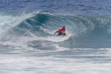 TENERIFE, SPAIN 11 - HAZİRAN 2013: Erkekler vücut tahtası şampiyonasında yarışan bir çocuğun dalgada dizlerinin üzerinde sörf yaparken farklı ve inanılmaz manevralar ve dönüşler yaparak bir sürü köpük oluşturduğu açık çekim. Tenerife, Kanarya Adaları, Spai