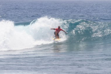 TENERIFE, SPAIN 11 - HAZİRAN 2013: Erkekler vücut tahtası şampiyonasında yarışan bir çocuğun dalgada dizlerinin üzerinde sörf yaparken farklı ve inanılmaz manevralar ve dönüşler yaparak bir sürü köpük oluşturduğu açık çekim. Tenerife, Kanarya Adaları, Spai