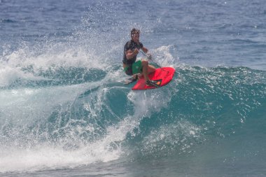 TENERIFE, SPAIN 11 - HAZİRAN 2013: Erkekler vücut tahtası şampiyonasında yarışan bir çocuğun dalgada dizlerinin üzerinde sörf yaparken farklı ve inanılmaz manevralar ve dönüşler yaparak bir sürü köpük oluşturduğu açık çekim. Tenerife, Kanarya Adaları, Spai