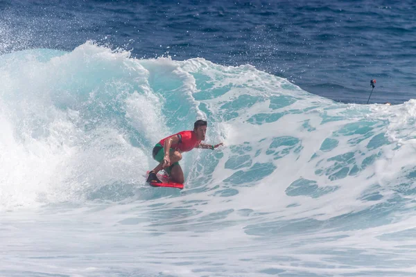 TENERIFE, SPAIN 11 - HAZİRAN 2013: Erkekler vücut tahtası şampiyonasında yarışan bir çocuğun dalgada dizlerinin üzerinde sörf yaparken farklı ve inanılmaz manevralar ve dönüşler yaparak bir sürü köpük oluşturduğu açık çekim. Tenerife, Kanarya Adaları, İspanya