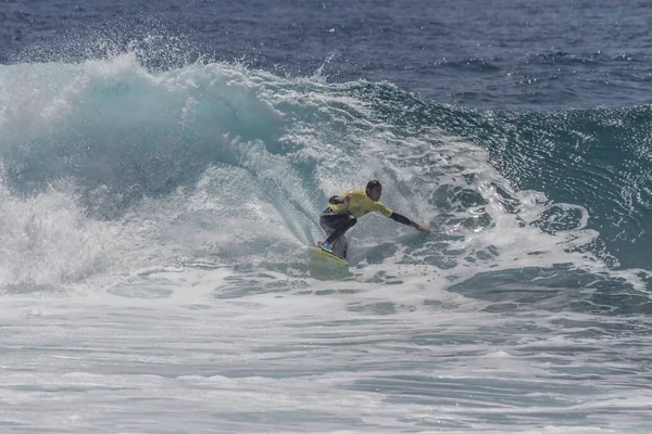 TENERIFE, SPAIN 11 - HAZİRAN 2013: Erkekler vücut tahtası şampiyonasında yarışan bir çocuğun dalgada dizlerinin üzerinde sörf yaparken farklı ve inanılmaz manevralar ve dönüşler yaparak bir sürü köpük oluşturduğu açık çekim. Tenerife, Kanarya Adaları, Spai