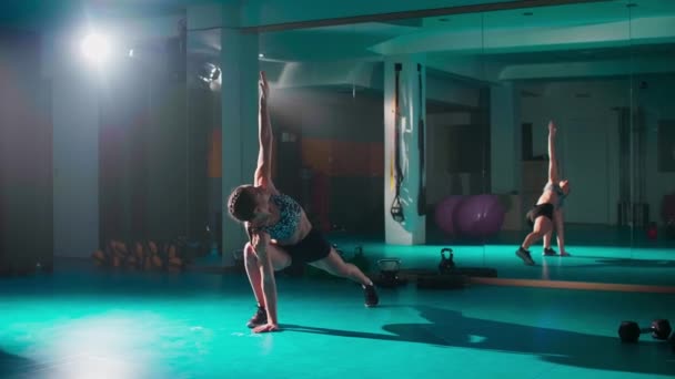 Μια Νεαρή Γυναίκα Τεντώνεται Στο Γυμναστήριο Μέσα Από Μια Άσκηση — Αρχείο Βίντεο