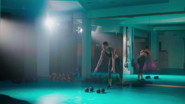 ジムで体重のある手の体操をしている若い女性が 他の運動器具が彼女の周りにある間 — ストック動画