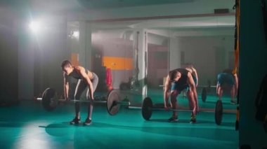 Bir kadın ve bir erkek birlikte antrenman yapıyor ve aynı zamanda spor salonunda ölü kaldırma egzersizi yapıyor..