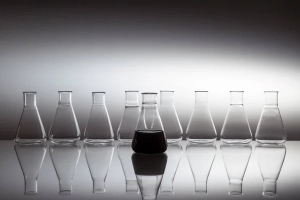 反射面にガラス器具で満たされた黒い液体で満たされた科学研究室のガラスエルレンマイヤーフラスコ — ストック写真