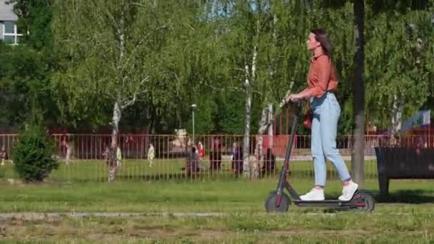 Ung Vacker Kvinna Rider Elektrisk Skoter Genom Parken Och Gröna — Stockvideo