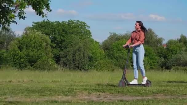 Młoda Piękna Kobieta Jeździ Skuterze Elektrycznym Parku Zielonym Otoczeniu Niektórych — Wideo stockowe