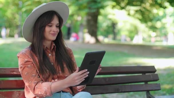 Uma Jovem Mulher Com Chapéu Está Sentada Banco Parque Rolando — Vídeo de Stock