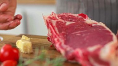 Aşçının ellerinin, tereyağını sürdüğü ve bir parça ete başka baharatlar kattığı hazırlık aşamasında yakın plan çekimi..