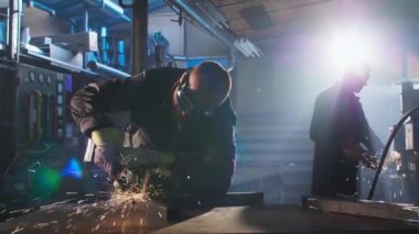 Atölyede çalışan ve arka planda çalışan bir meslektaşın yakın çekimi. Koruyucu gözlük takıyor..