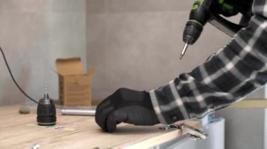 Marangoz mutfak raf kapısının mekanizmalarını (eklemlerini) kurar ve vidalar.