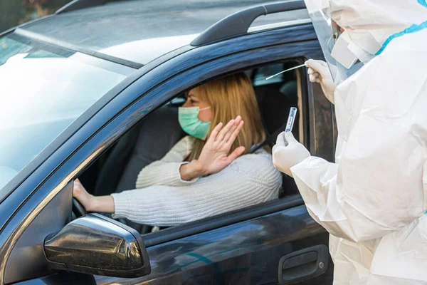 Kadın sürüş sırasında COVID 19 testi yapmayı reddediyor. Hastanın burnundan araba camından DNA örneği alıyor. PCR teşhisi koyuyor. Pasaportları var..