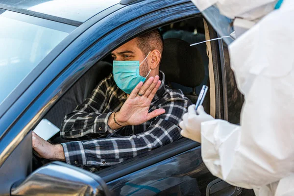 Adam sürüş sırasında COVID 19 testi yapmayı reddediyor. Hastanın burnundan araba camından DNA örneği alıyor. PCR teşhisi koyuyor. Pasaportları var..
