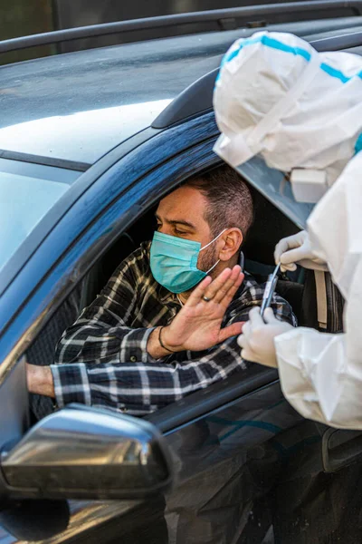 Adam sürüş sırasında COVID 19 testi yapmayı reddediyor. Hastanın burnundan araba camından DNA örneği alıyor. PCR teşhisi koyuyor. Pasaportları var..