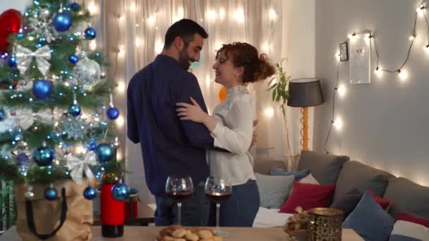 Pohledný muž a krásná žena tančí u vánočního stromku v obývacím pokoji. Příprava a oslava svátků