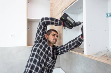 Marangoz duvardaki mutfak rafının montajını tamamlıyor..