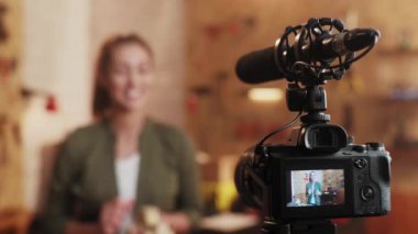 Marangozluk atölyesindeki DIY blogu için sette kamera önünde duran kadın. Marangoz ahşap oyuncaklardan bahsediyor. Kameraya odaklan..