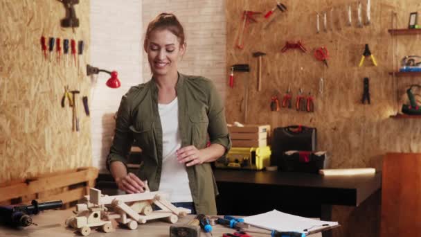 木匠作坊里女人的画像 笑着展示木制玩具 — 图库视频影像