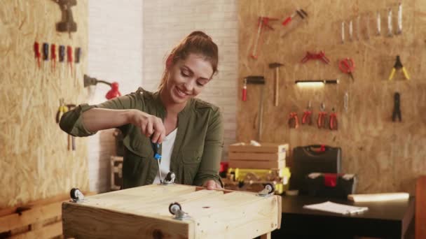 木匠作坊里女人的画像用螺丝刀完成螺丝 用轮子完成木箱的最后作品 — 图库视频影像