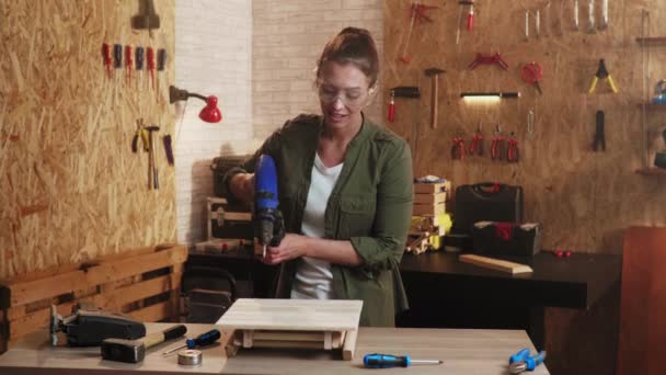 车间里的女木匠 戴着安全护目镜 在木椅上操练 — 图库视频影像