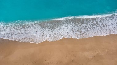 Güzel kumlu sahil manzarası ve yumuşak turkuaz okyanus dalgası. Yaz mevsiminde Lefkada adasındaki Megali Petra plajında tropikal deniz.