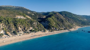 Güneş gözlüklü ve yumuşak turkuaz okyanus dalgalı güzel kumlu sahil manzarası. Yaz mevsiminde Lefkada adasındaki Kathisma plajında tropik deniz..