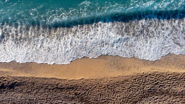 Güzel kumlu sahil manzarası, ayak izleri ve yumuşak turkuaz okyanus dalgası. Yaz mevsiminde Lefkada adasındaki Kathisma plajında tropik deniz..